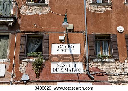 Stock Image - Street signs on a house facade, Venice, Italy, low angle view . Fotosearch