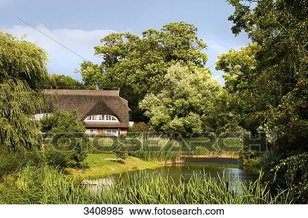 Stock Photography - Thatched-roof house at a pond, Middelhagen, Ruegen, Germany . Fotosearch