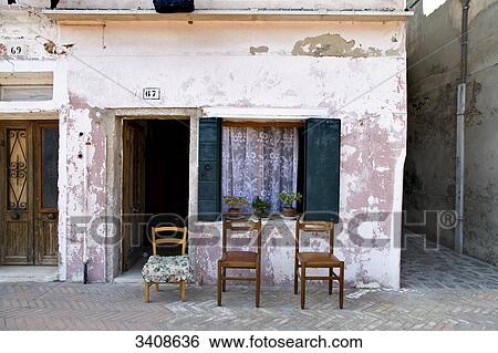 Stock Photograph - Three chairs in front of an old house, Burano, Italy . Fotosearch