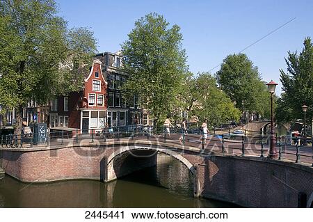 Stock Image - Three people walking on bridge, Kaizersgracht, Amsterdam, Netherlands . Fotosearch