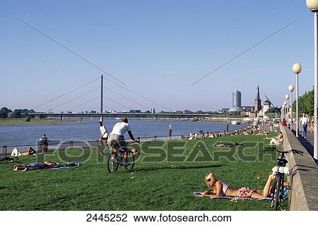Stock Image - Tourists at riverbank, Rhine River, Dusseldorf, Rhineland, Germany . Fotosearch
