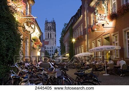 Stock Photography - Tourists at sidewalk cafe in street during dusk . Fotosearch