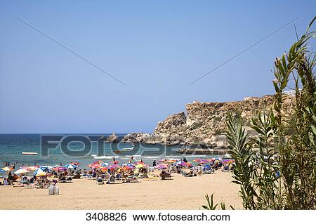 Stock Photograph - Tourists on the beach, Golden Bay, Malta . Fotosearch