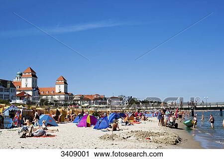 Stock Image - Tourists on the beach of Binz, spa hotel in the background, Ruegen, Germany . Fotosearch