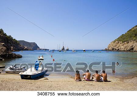 Tourists on the beach of Cala Benirras, Ibiza, Spain View Large Photo Image Stock Photography - Tourists on the beach of Cala Benirras, Ibiza, Spain . Fotosearch