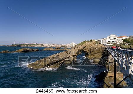 Tourists walking on bridge near natural arch with lighthouse in background, Pointe Saint-Martin, Biarritz, Pyrenees-Atlantiques, Aquitaine, France View Large Photo Image Stock Photo - Tourists walking on bridge near natural arch with lighthouse in background, Pointe Saint-Martin, Biarritz, Pyrenees-Atlantiques, Aquitaine, France . Fotosearch