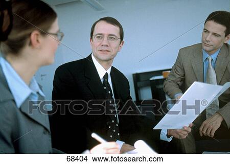 Picture - Two businessmen and businesswoman discussing in meeting . Fotosearch