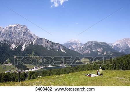 Two hikers on a meadow, view of Monte Cristallo and Lago di Misurina, Venetia, Italy, elevated view View Large Photo Image Stock Image - Two hikers on a meadow, view of Monte Cristallo and Lago di Misurina, Venetia, Italy, elevated view . Fotosearch