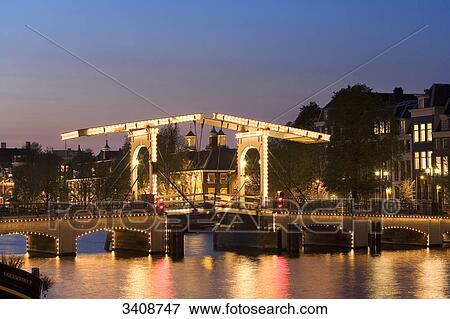 Stock Photo - View of Amstel River and Magere Brug in the evening, Amsterdam, Netherlands . Fotosearch
