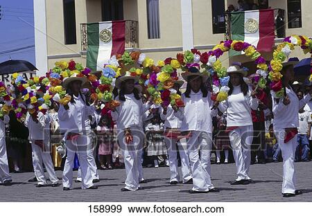 Stock Photo - Women carrying floral decorations during independence day parade, Mexico . Fotosearch