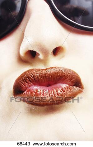 Stock Image - Young woman with sunglasses and red lips, detail . Fotosearch