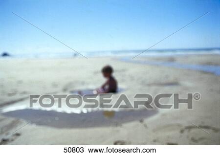 Blurred view of boy sitting in water on beach View Large Photo Image Stock Image - Blurred view of boy sitting in water on beach . Fotosearch