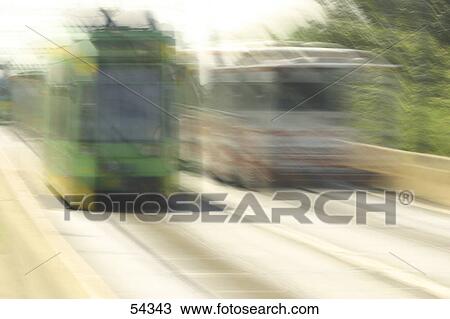 Stock Image - Blurred view of buses in motion on road . Fotosearch