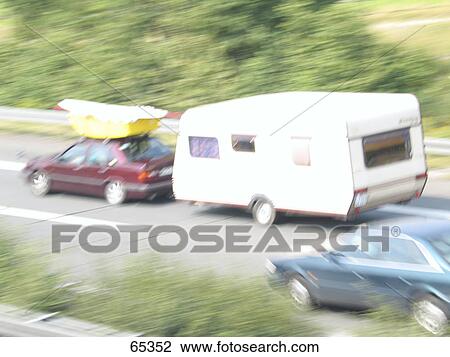 Stock Image - Blurred view of caravan and cars on road . Fotosearch