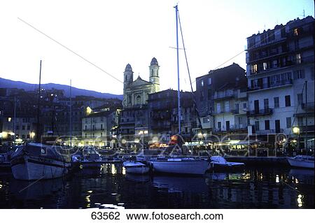 Stock Image - Boats in harbor lit up at dusk, Bastia, France . Fotosearch