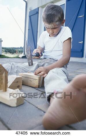 Boy hammering nail on wood View Large Photo Image Stock Photography - Boy hammering nail on wood . Fotosearch