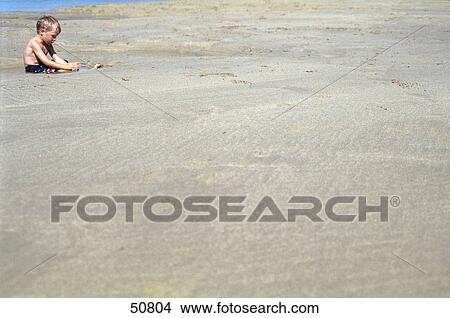 Boy sitting in water on beach View Large Photo Image Picture - Boy sitting in water on beach . Fotosearch