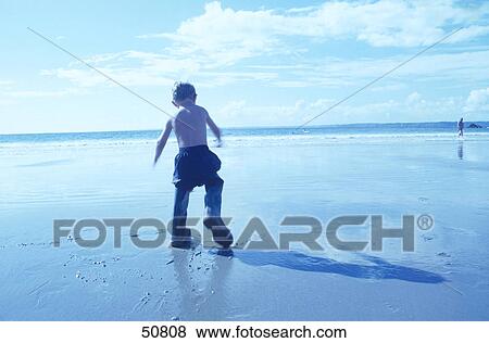 Boy walking at beach, rear view View Large Photo Image Stock Photo - Boy walking at beach, rear view . Fotosearch