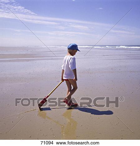 Boy walking with shovel on beach View Large Photo Image Picture - Boy walking with shovel on beach . Fotosearch
