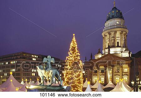 Stock Photograph - Christmas market in front of lit up church at dusk, Gendarmenmarkt, Berlin, Germany . Fotosearch