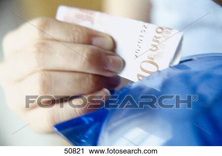 Close-up of person's hand putting ten euro banknote into piggy bank View Large Photo Image Stock Image - Close-up of person's hand putting ten euro banknote into piggy bank . Fotosearch