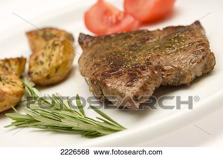 Stock Photo - Close-up of roasted beef and potatoes with slices of tomato on plate . Fotosearch
