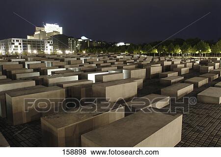 Concrete steles at memorial with building lit up at night in background, Holocaust Memorial, Berlin, Germany View Large Photo Image Stock Photo - Concrete steles at memorial with building lit up at night in background, Holocaust Memorial, Berlin, Germany . Fotosearch