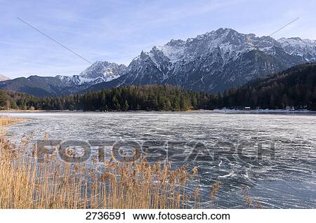 Stock Image - Frozen lake in front of forest, Lautersee, Bavaria, Germany . Fotosearch
