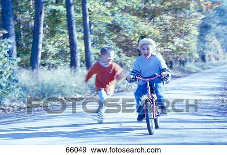 Girl riding bicycle with her brother running behind her, Landstrasse, Vienna, Austria View Large Photo Image Stock Photo - Girl riding bicycle with her brother running behind her, Landstrasse, Vienna, Austria . Fotosearch