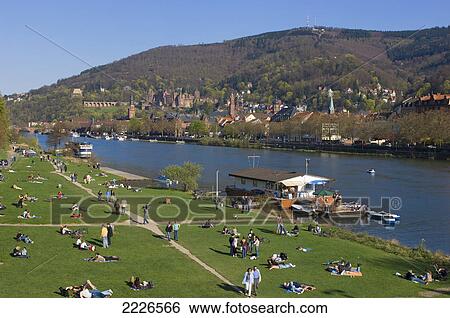 Group of tourists relaxing on riverside, River Neckar, Heidelberg, Germany View Large Photo Image Stock Photograph - Group of tourists relaxing on riverside, River Neckar, Heidelberg, Germany . Fotosearch