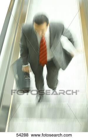 High angle view of businessman holding suitcase on escalator View Large Photo Image Stock Photo - High angle view of businessman holding suitcase on escalator . Fotosearch