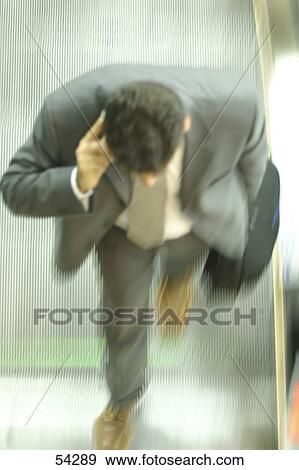 Stock Photo - High angle view of businessman talking on escalator . Fotosearch