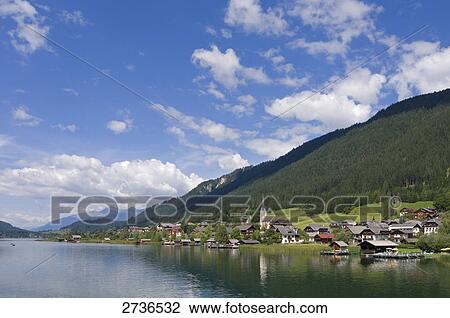 Stock Image - Houses and church at lakeside, Weissensee, Techendorf, Carinthia, Austria . Fotosearch