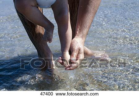 Low section view of man washing his baby's feet View Large Photo Image Stock Image - Low section view of man washing his baby's feet . Fotosearch