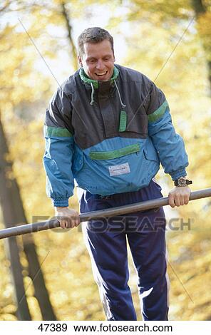 Man exercising on pole and smiling in park View Large Photo Image Stock Photo - Man exercising on pole and smiling in park . Fotosearch