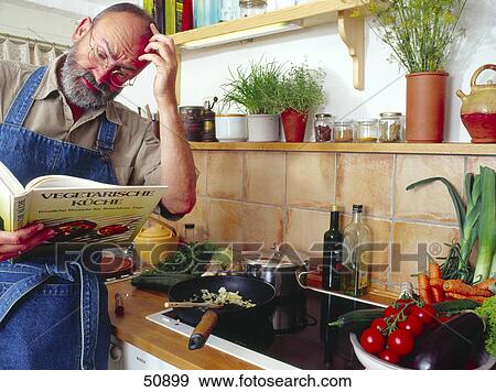Stock Photo - Man reading cookbook in kitchen . Fotosearch