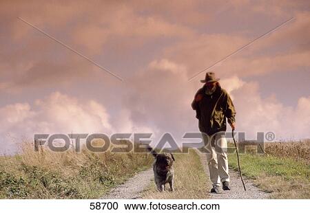 Man walking with dog on dirt road View Large Photo Image Stock Image - Man walking with dog on dirt road . Fotosearch