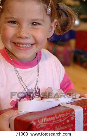 Portrait of girl holding christmas gift and smiling View Large Photo Image Stock Image - Portrait of girl holding christmas gift and smiling . Fotosearch