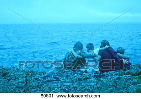 Rear view of four children sitting on rock at coast View Large Photo Image Stock Image - Rear view of four children sitting on rock at coast . Fotosearch