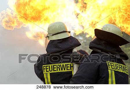 Rear view of two firefighters extinguishing fire View Large Photo Image Stock Photo - Rear view of two firefighters extinguishing fire . Fotosearch