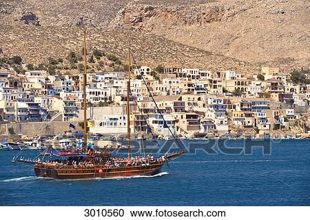 Stock Image - Sailing vessel occupied by tourists in front of the coast of Kalymnos, Greece . Fotosearch