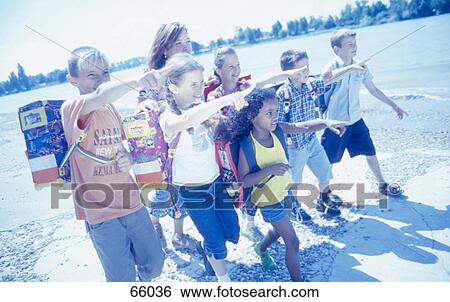 Stock Photograph - School students walking on beach and pointing . Fotosearch
