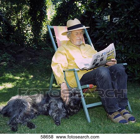 Senior man sitting with dog and reading newspaper View Large Photo Image Stock Photo - Senior man sitting with dog and reading newspaper . Fotosearch