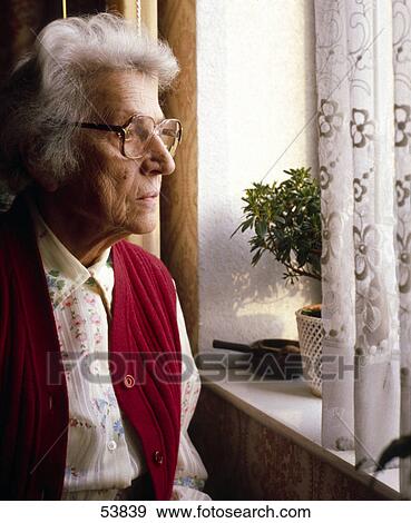 Senior woman looking through window View Large Photo Image Stock Photo - Senior woman looking through window . Fotosearch