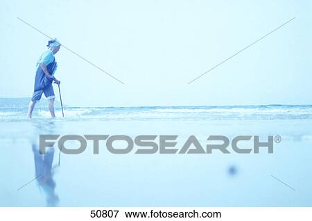 Senior woman walking with cane on beach View Large Photo Image Stock Photo - Senior woman walking with cane on beach . Fotosearch