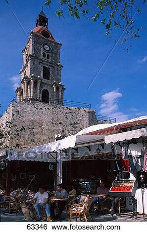 Tourists at outdoor cafe in front of clock tower, Rhodes, Dodecanese Islands, Greece View Large Photo Image Stock Photograph - Tourists at outdoor cafe in front of clock tower, Rhodes, Dodecanese Islands, Greece . Fotosearch