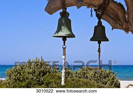 Stock Image - Two bells hanging on a limb of a tree, Cos, Greece . Fotosearch