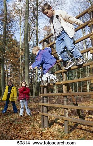 Two boys playing on monkey bars with two girls standing in background View Large Photo Image Picture - Two boys playing on monkey bars with two girls standing in background . Fotosearch