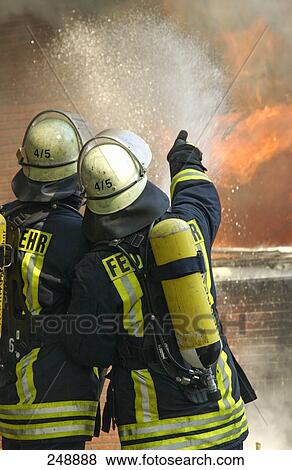 Stock Photo - Two firemen extinguishing fire in house . Fotosearch