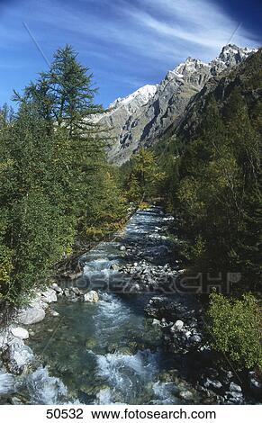 Water flowing in creek with mountain in background, Switzerland View Large Photo Image Stock Image - Water flowing in creek with mountain in background, Switzerland . Fotosearch